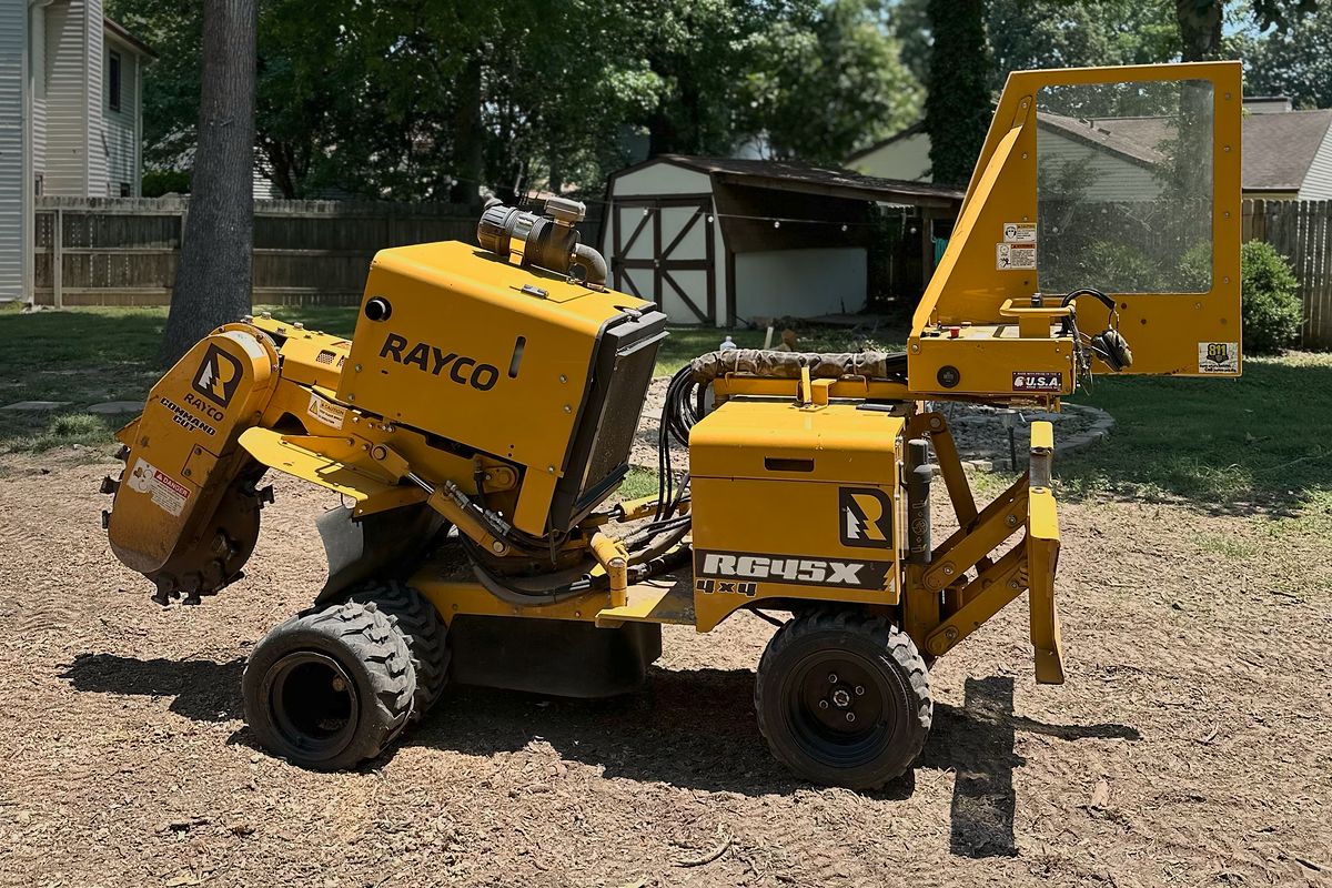 Yellow Rayco RG45X stump grinder parked on wood chips in a fenced backyard