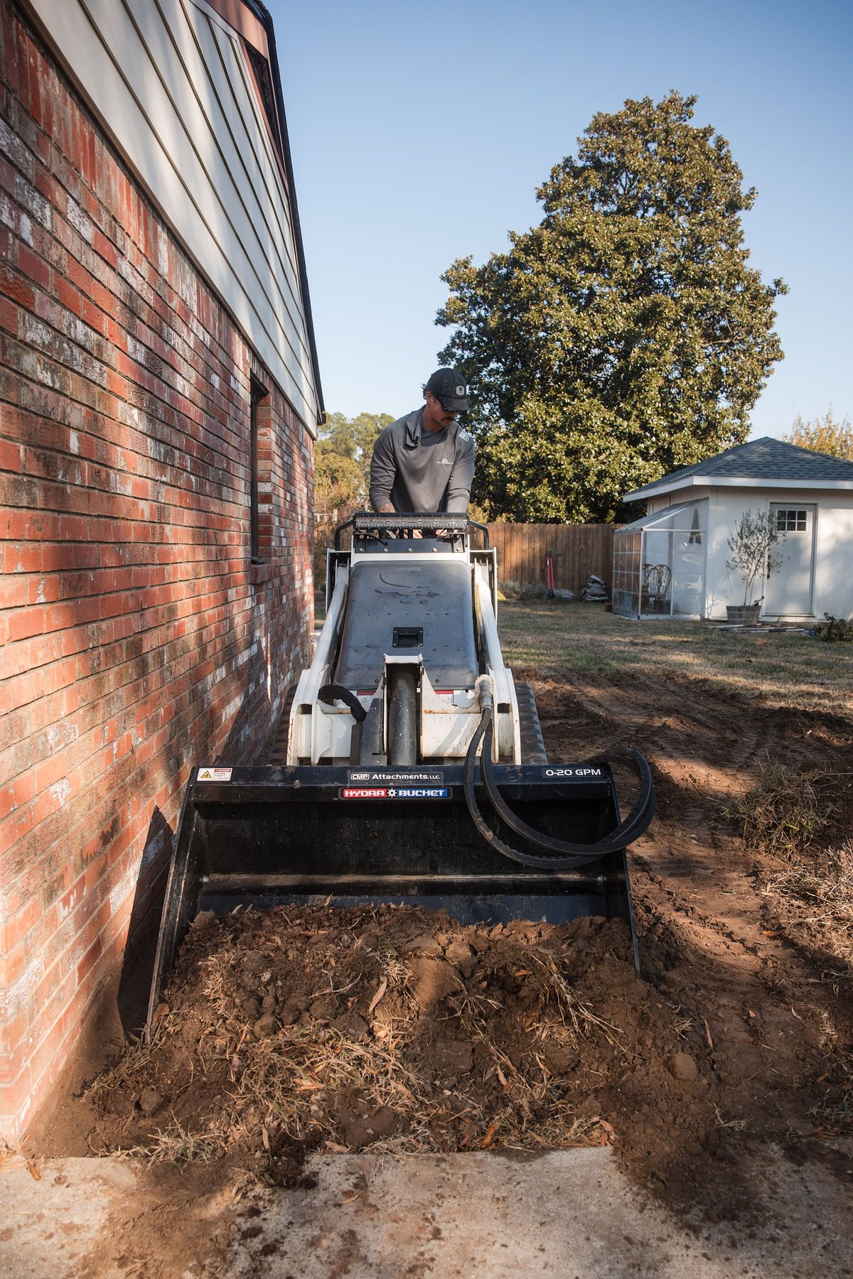Mini track loader along the side of a house